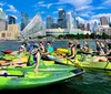 A man and a woman are kayaking in front of an urban skyline