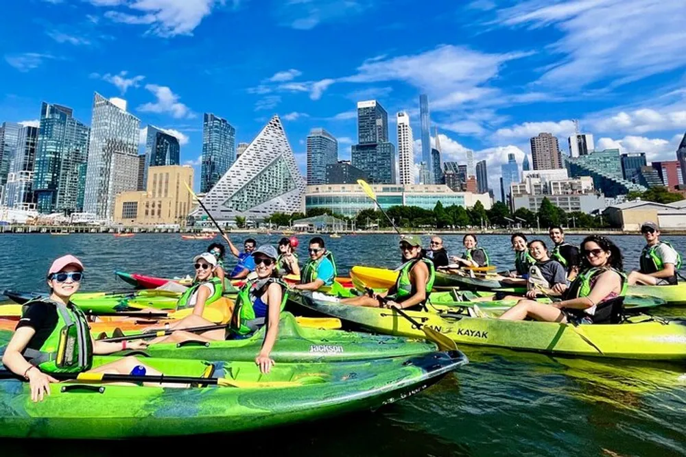 A group of kayakers enjoys a sunny day on the water with a backdrop of modern skyscrapers