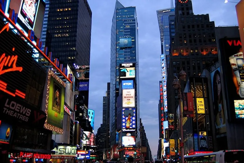 The image shows the bright and bustling Times Square in New York City at twilight teeming with illuminated billboards and advertisements