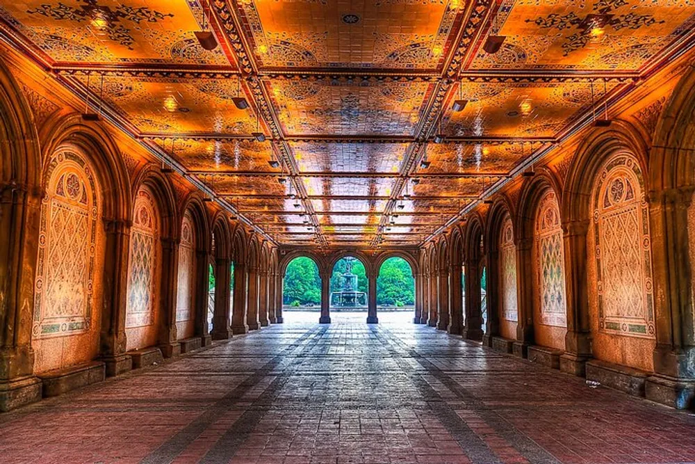 The image depicts a lavishly ornate covered arcade with an intricately designed ceiling and arches opening toward a bright leafy park