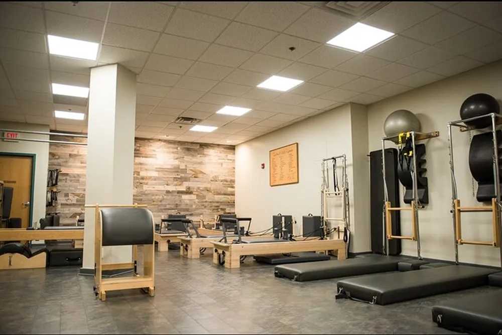 The image shows a well-equipped Pilates studio with various exercise machines and accessories