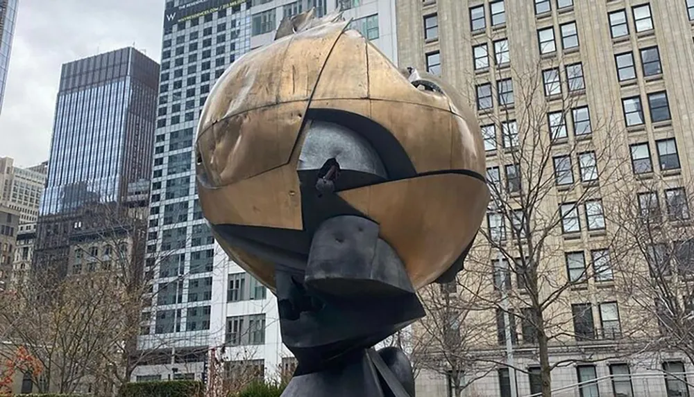 The image displays the iconic bronze sculpture known as The Sphere by Fritz Koenig which is a monument that survived the 911 attacks and now stands as a symbol of resilience and peace