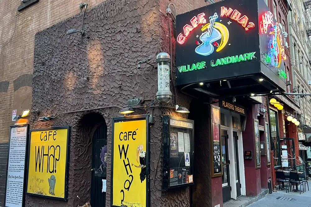 The image shows the exterior of Caf Wha a venue with a colorful neon sign declared as a village landmark featuring a brown textured facade and yellow signage at the entrance