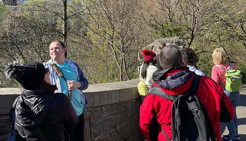 A group of people is enjoying a sunny day outdoors some looking out at the view while one person faces the camera with a smile