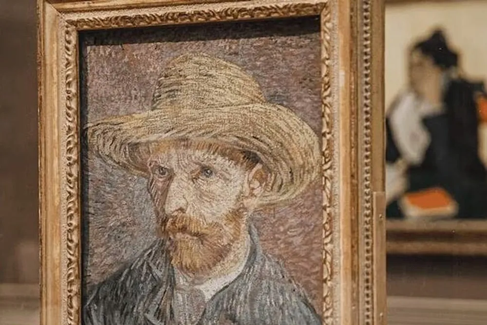 The image shows a framed painting of a man with a straw hat and beard displayed in an art gallery with another piece of art visible in the background