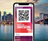 A smartphone is displaying a QR code for The New York Sightseeing Pass against the backdrop of a city skyline at twilight