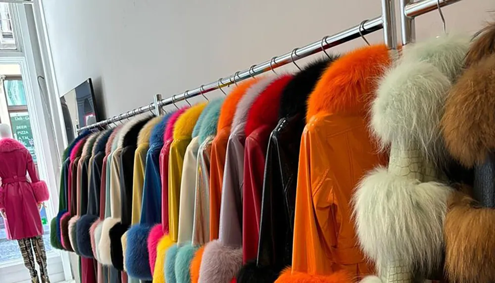 The image shows a clothing rack with a vibrant array of fur-trimmed jackets in various colors displayed in a boutique or store