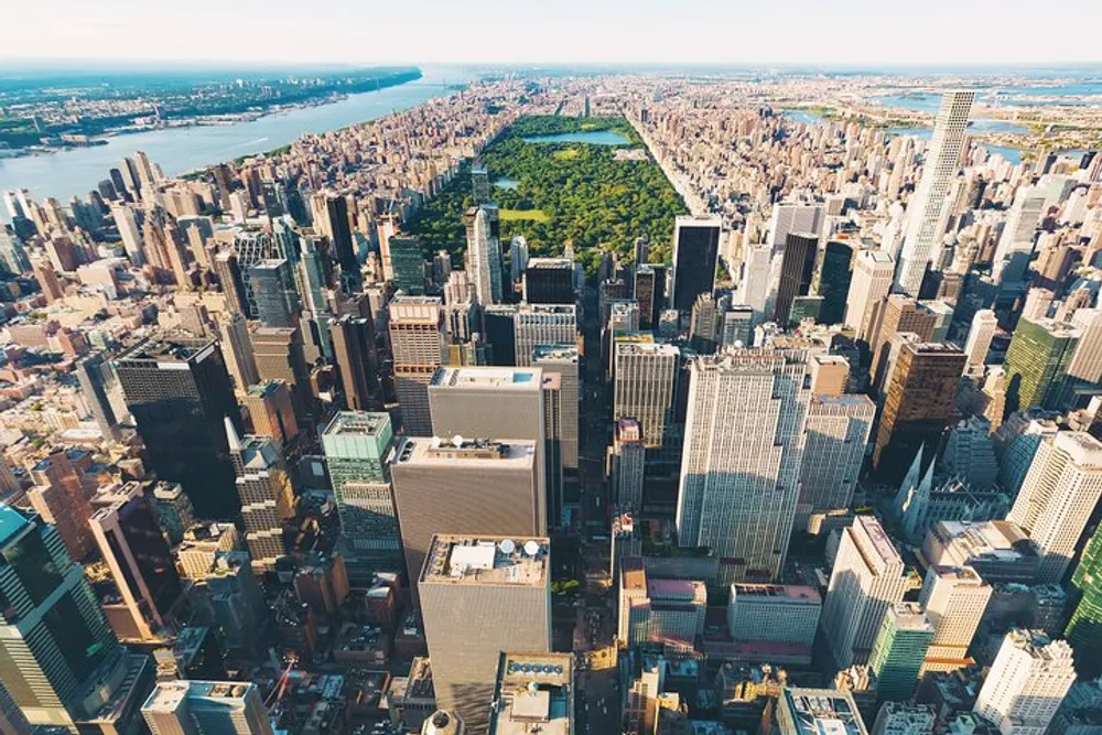 This image features an aerial view of a dense urban skyline with numerous high-rise buildings leading up to a large elongated central park suggesting it may be a photograph of Midtown Manhattan in New York City