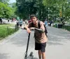 An electric scooter stands abandoned by an ornate metal fence with a scenic view of a city skyline across a body of water