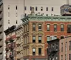 The image depicts a bustling early 20th-century street scene with an elevated train track horse-drawn carriages and vintage automobiles showcasing a vivid snapshot of urban life during that era