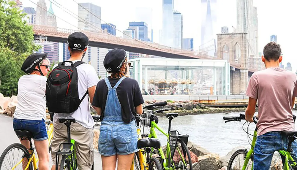 A group of cyclists pauses to view a scenic cityscape with a bridge in the background