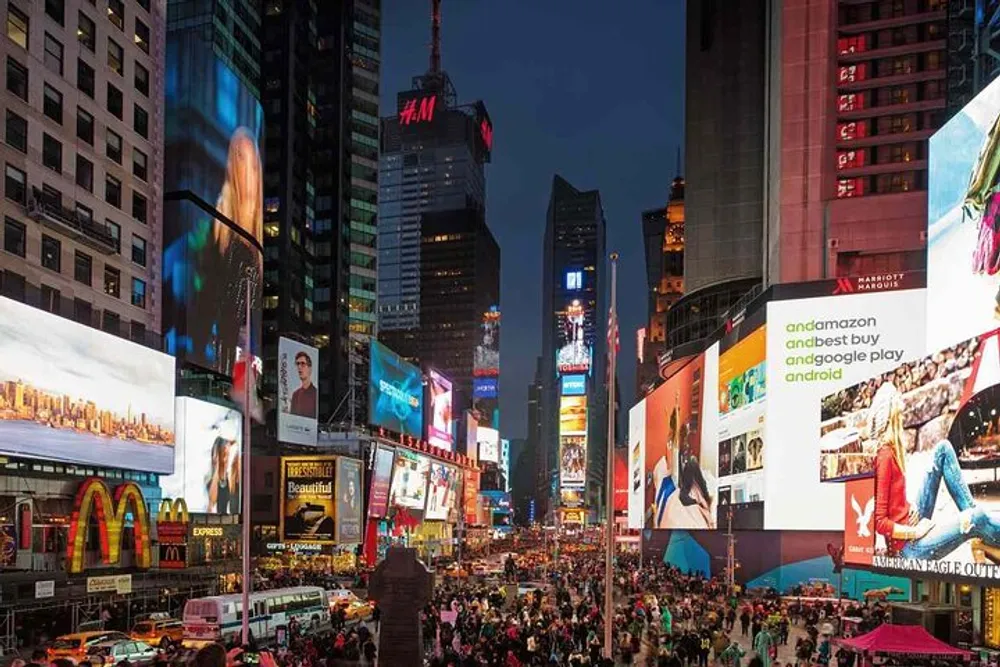 The image shows the vibrant Times Square in New York City at dusk bustling with people and illuminated by numerous bright digital billboards