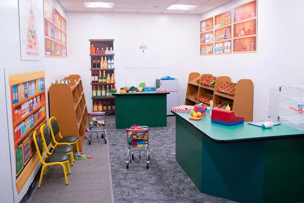 The image shows a colorful child-friendly room with toy shelves a play grocery store setup chairs for children and various play items suggesting a space designed for early childhood education or play