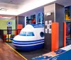 The image shows an indoor playground with colorful floors and scattered soft balls featuring play structures for childrens entertainment