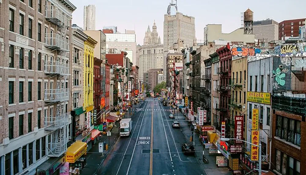 This image captures a vibrant street scene likely from a Chinatown district with colorful storefronts assorted signage and urban architecture against a backdrop of taller city buildings