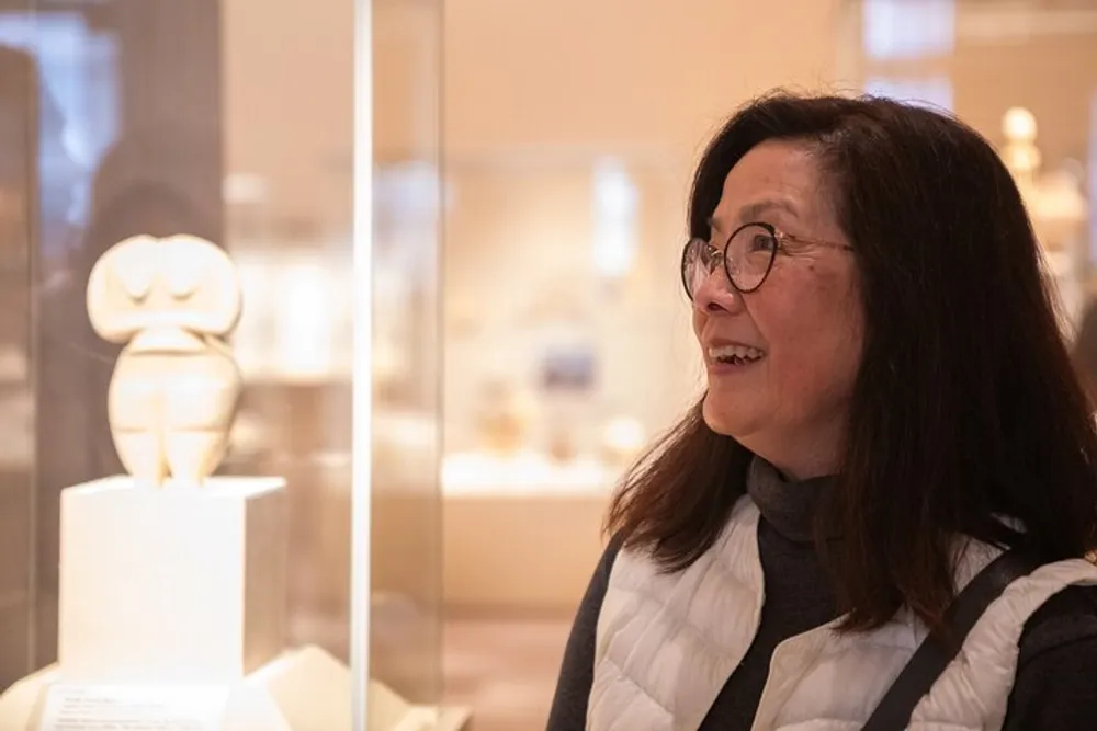 A person is admiring an exhibit within a glass display in what appears to be a museum setting