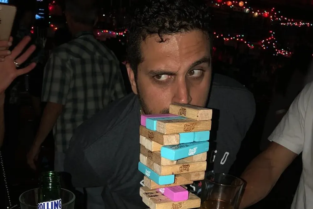 A person appears to be intently staring at a tower of Jenga blocks implying a high-stakes moment in the game