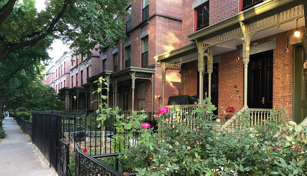 The image depicts a calm residential street lined with charming brick row houses featuring front porches and greenery