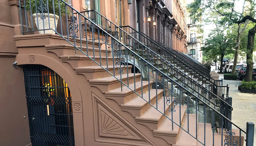 This image depicts the classic architectural detail of brownstone steps and metal railings along a tree-lined sidewalk in what appears to be an urban residential neighborhood