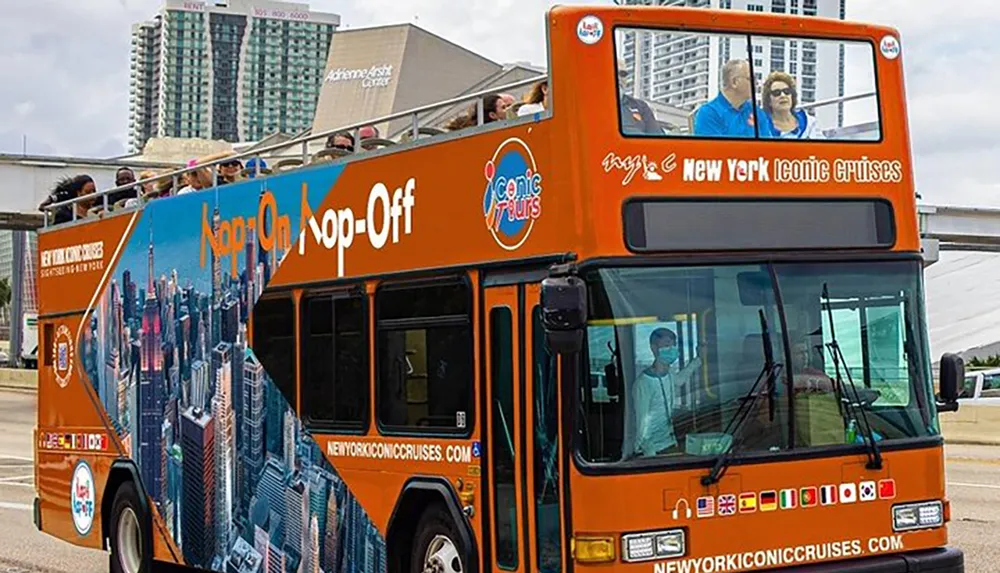 A double-decker tour bus with the words New York Iconic Cruises is parked displaying an Hop On Hop-Off advertisement with passengers visible on the upper open-air deck