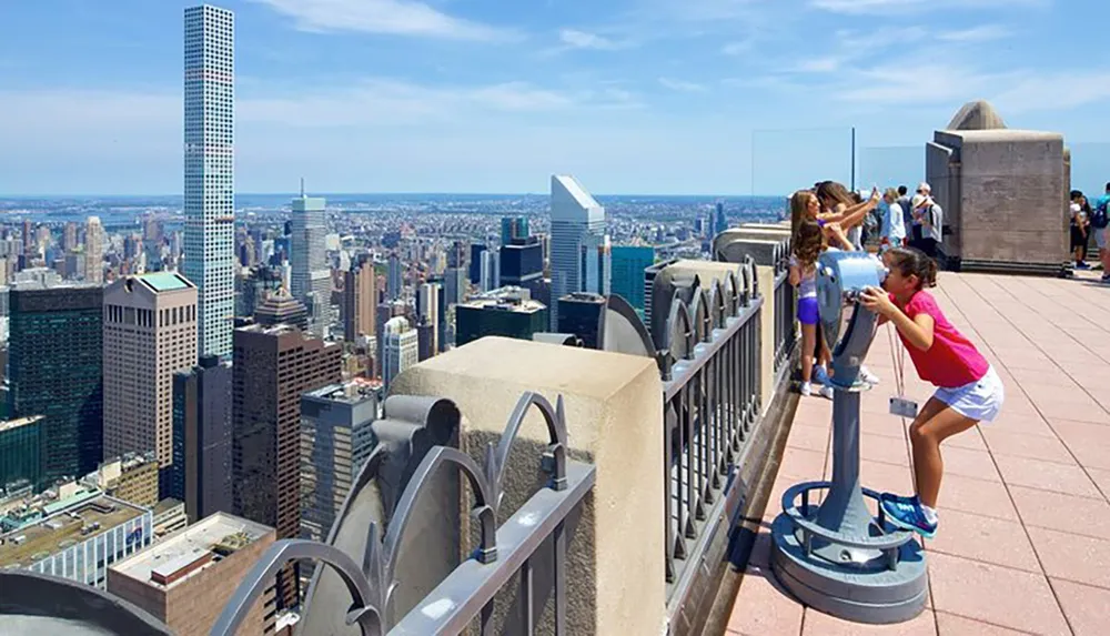 Visitors enjoy the view of a sprawling cityscape from a high vantage point with coin-operated binoculars available for a closer look