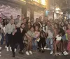 A large group of smiling people posing for a photo on a lively urban street at night