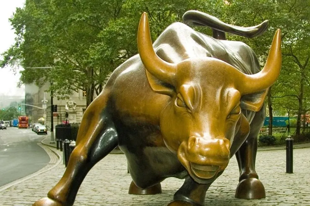 The image shows the Charging Bull statue a symbol of Wall Street set against a backdrop of tree-lined streets and New York Citys urban environment