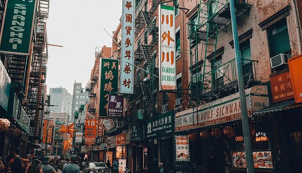 The image shows a bustling street lined with Chinese signage fire escapes and pedestrians reflecting an urban Chinatown ambiance