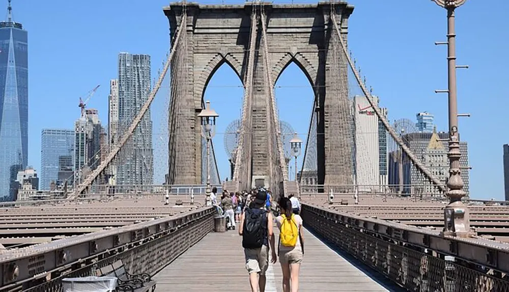 A bustling scene on the walkway of the Brooklyn Bridge with pedestrians and the New York City skyline in the background