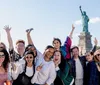 A group of cheerful people are posing for a photo with the Statue of Liberty in the background