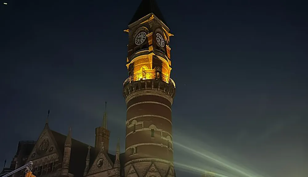 The image shows a beautifully illuminated brick clock tower against a dusky sky with rays of light emanating from below