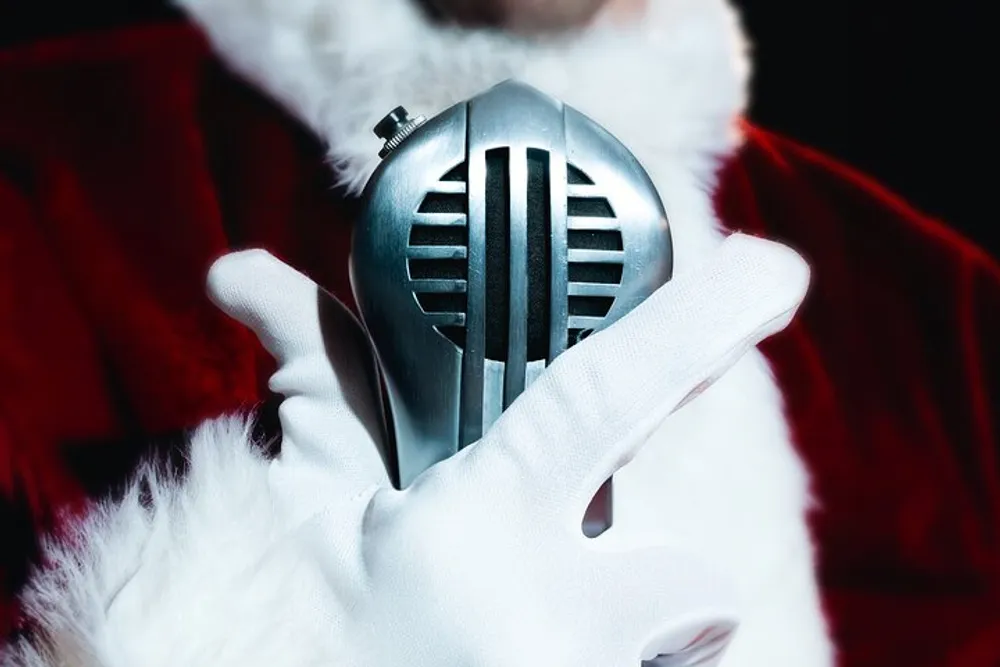 A person dressed as Santa Claus is holding a vintage microphone