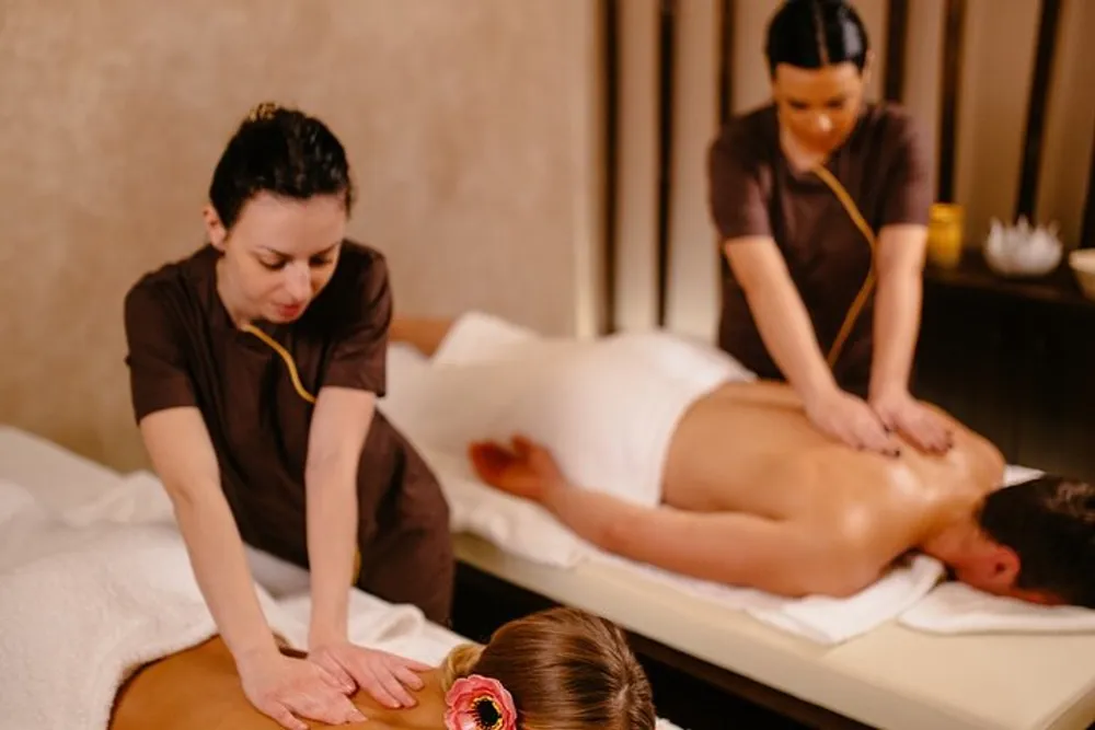 Two massage therapists are providing a relaxing treatment to clients in a serene spa setting