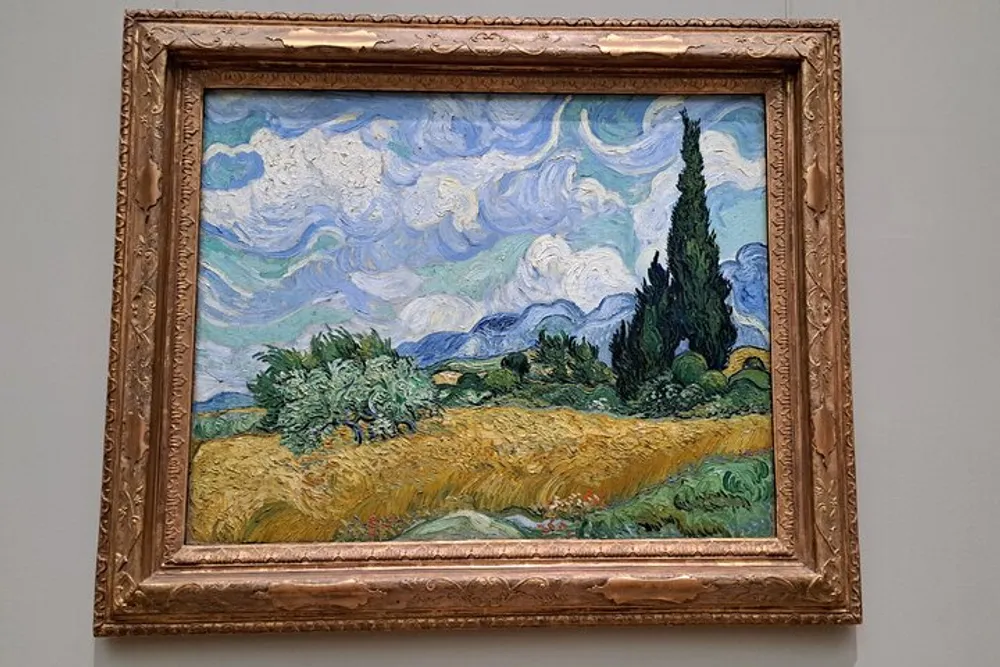 The image shows a framed painting with an impressionist style depicting a vibrant landscape with swirling clouds a golden field and greenery characteristic of Vincent van Goghs artwork