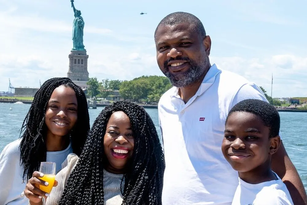 A happy family is posing for a photo in front of the Statue of Liberty on a sunny day