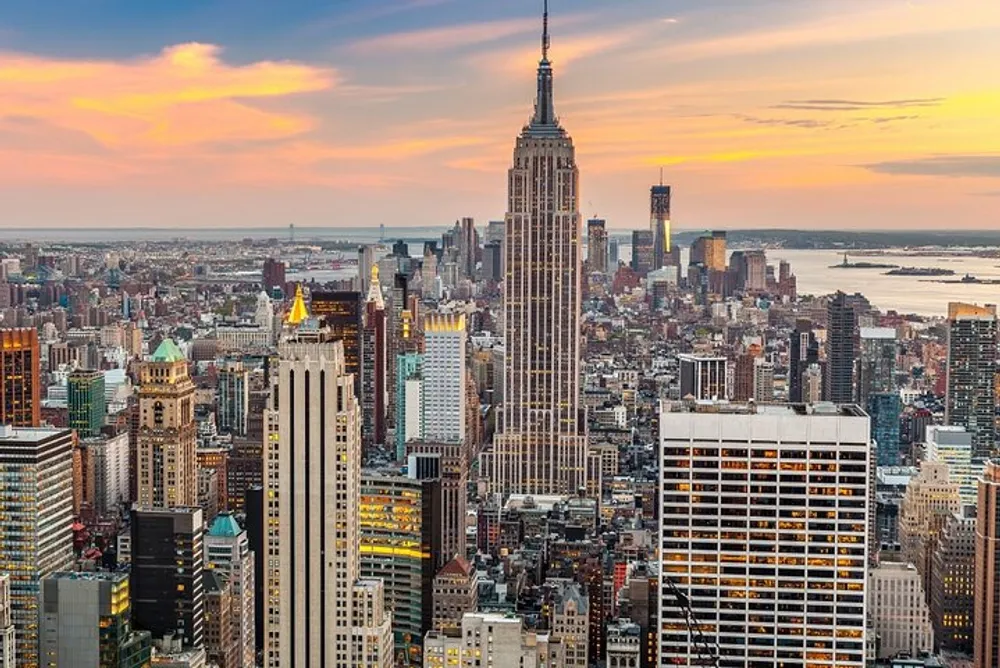 The image shows a panoramic view of the New York City skyline featuring the Empire State Building at sunset