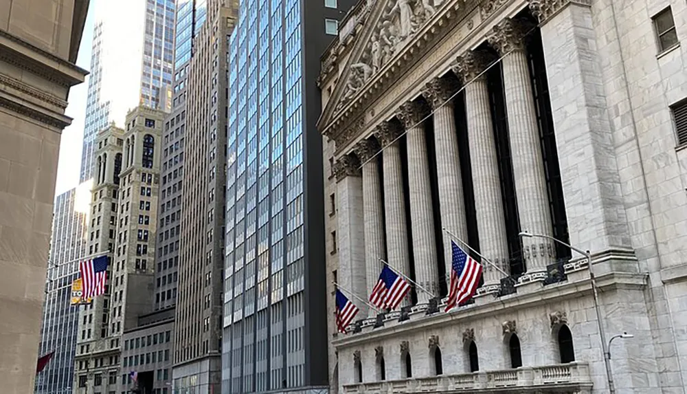 This image features a scene of a neoclassical building with tall sturdy columns and American flags juxtaposed against modern skyscrapers likely depicting a financial district