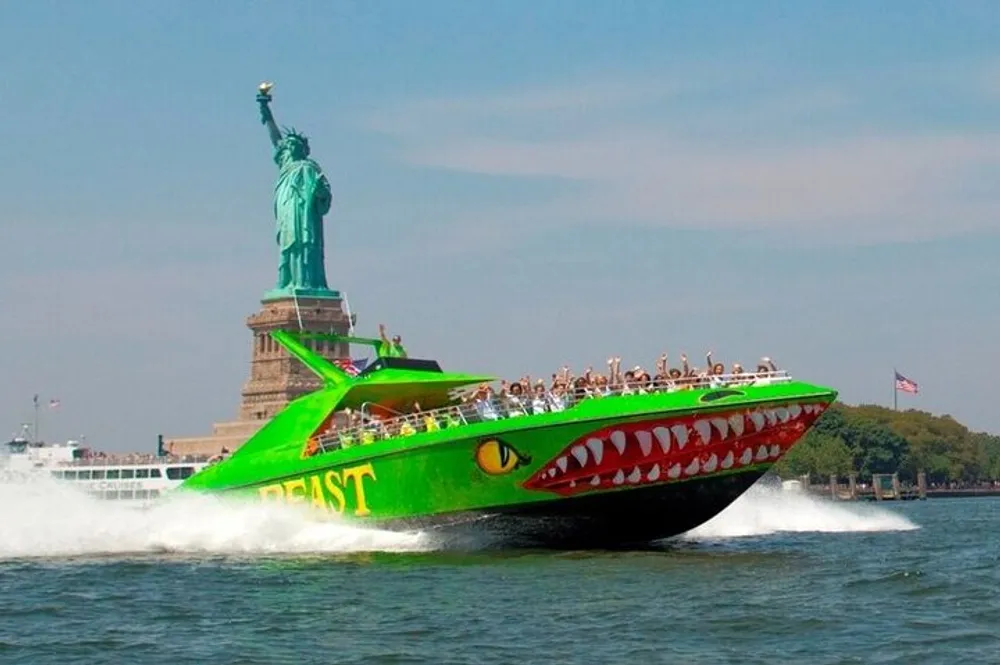 A speedboat adorned with shark-like features speeds through the water with passengers onboard against the backdrop of the Statue of Liberty