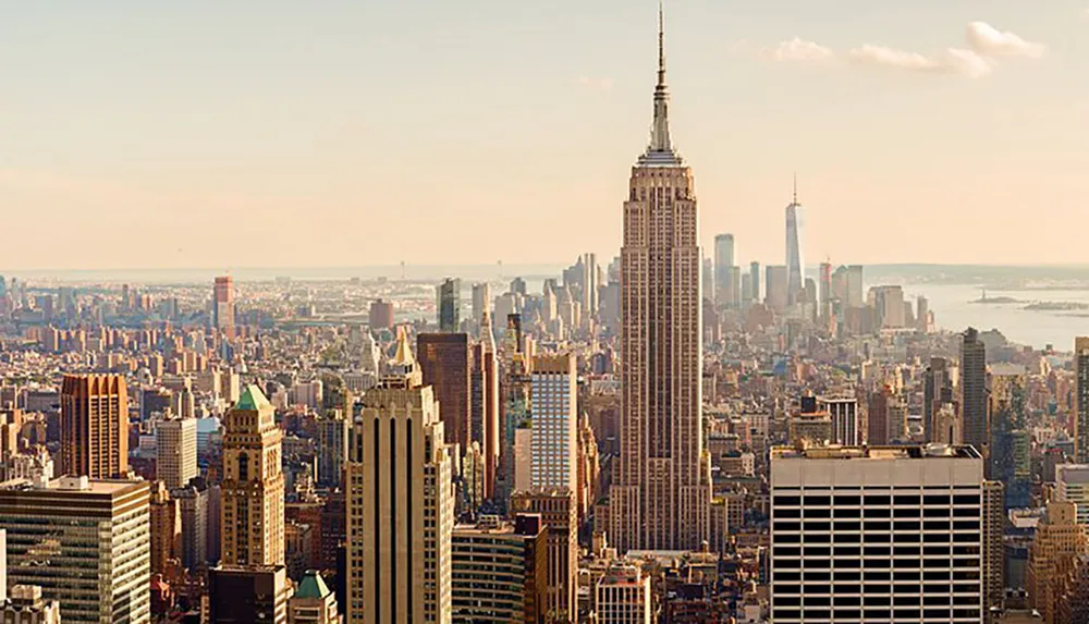 The image captures a panoramic view of the iconic New York City skyline featuring the Empire State Building as a prominent structure in the foreground