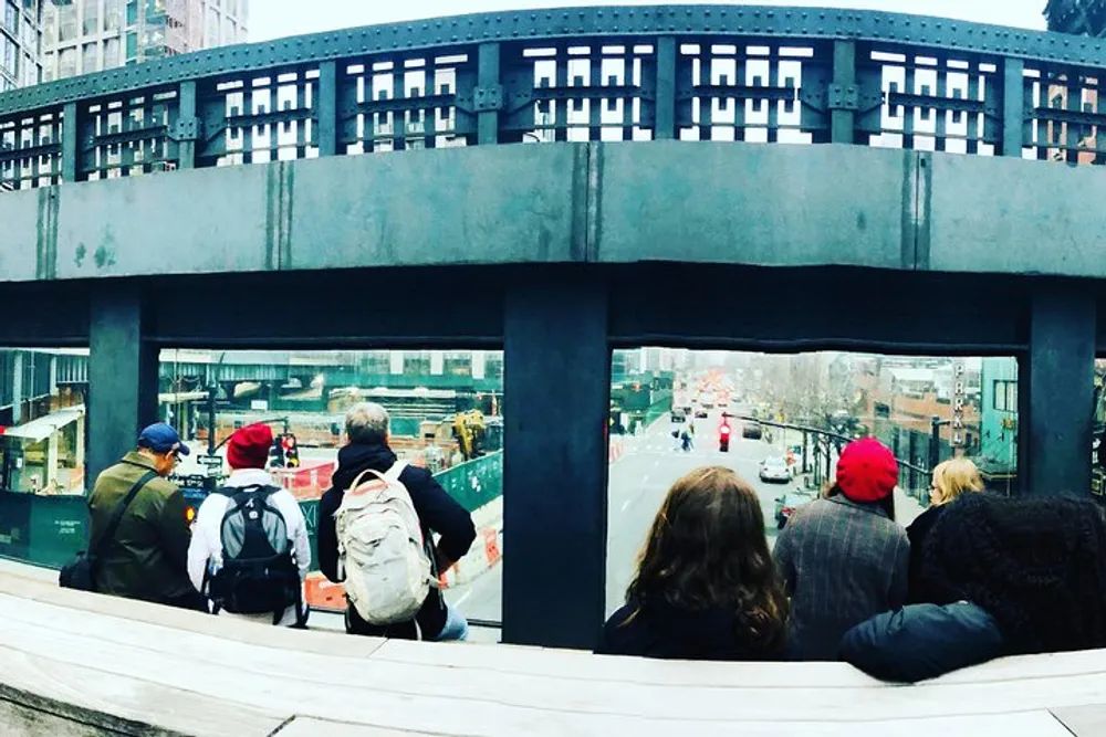 People are sitting and looking through a large window-like structure at a bustling city street below