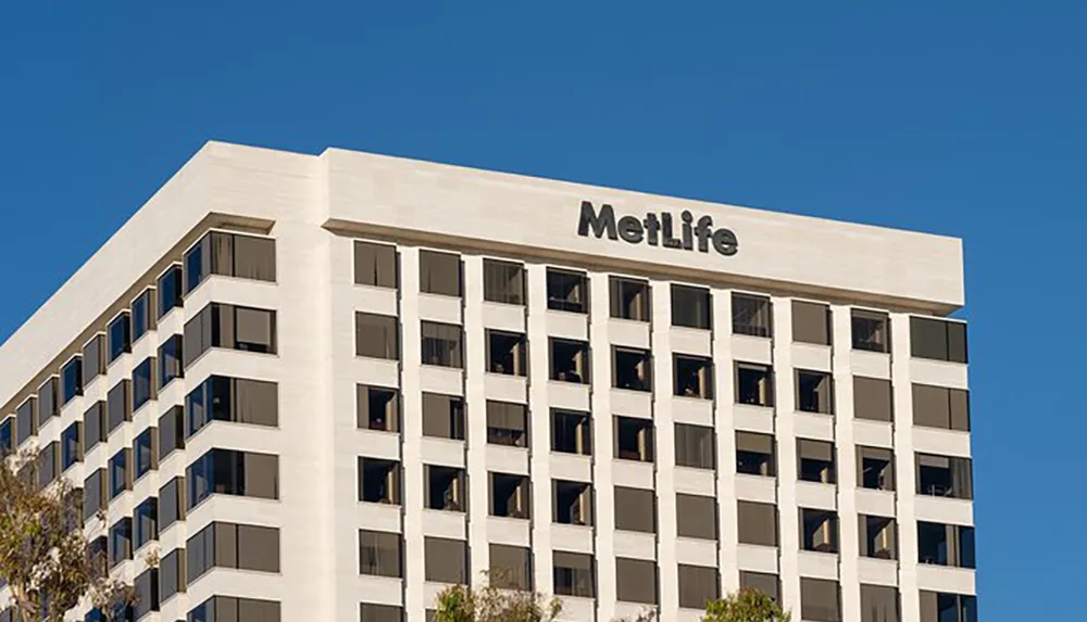 The image shows the upper facade of a modern building with the MetLife logo prominently displayed against a clear blue sky