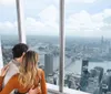 A couple is enjoying a scenic view of a cityscape from a high vantage point with large windows