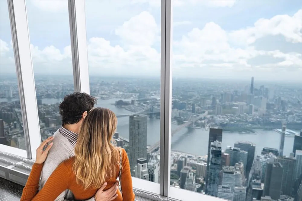 A couple is enjoying a scenic view of a cityscape from a high vantage point with large windows