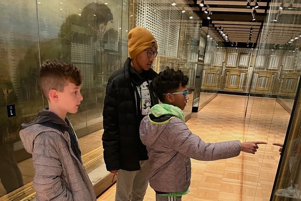 Three individuals appear to be engaged in observing and discussing an exhibit on display in a museum-like setting