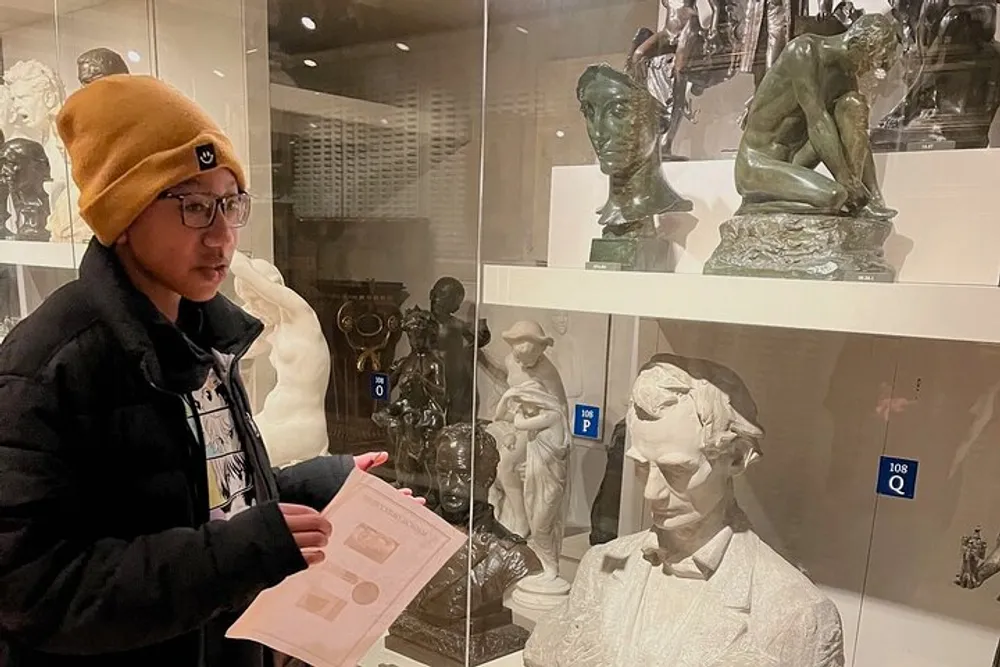 A person is viewing various sculptures displayed in a glass case in an art gallery or museum