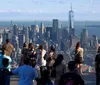 Visitors enjoy a panoramic view of a city skyline from a high vantage point with protective glass barriers