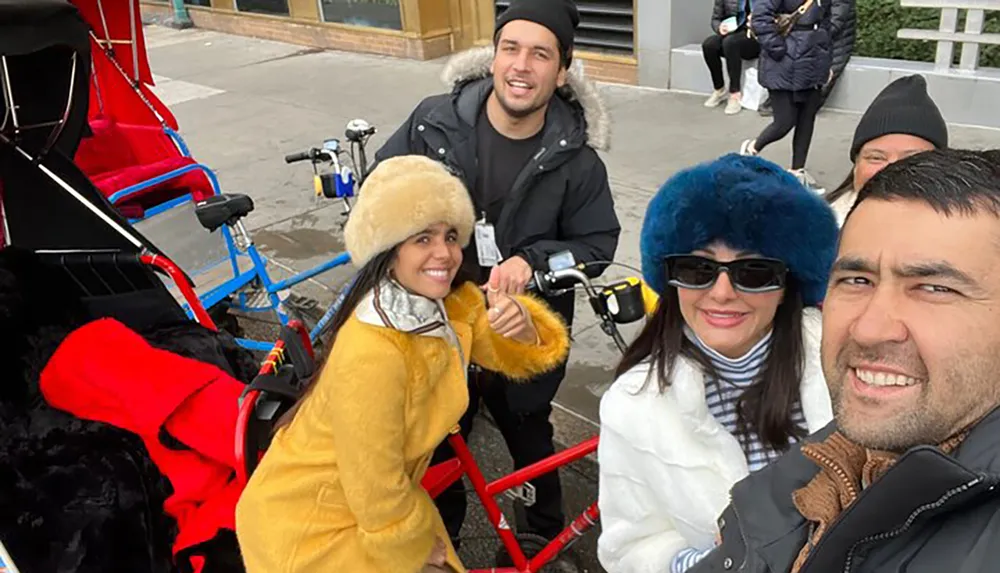 A group of smiling people are posing for a photo on what appears to be a pedal-powered quadricycle clad in winter attire