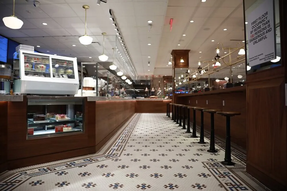 The image shows an empty clean diner with a classic design featuring a dessert case tiled floor and a row of stools along a countertop