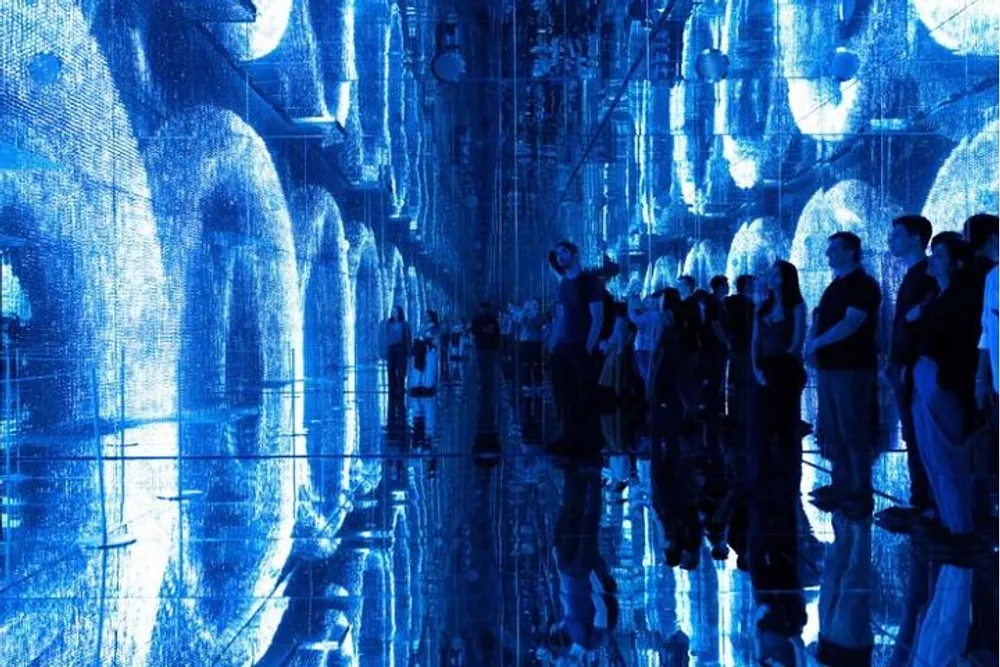 Visitors are immersed in an illuminated blue digital art installation that creates an ethereal mirror-like experience