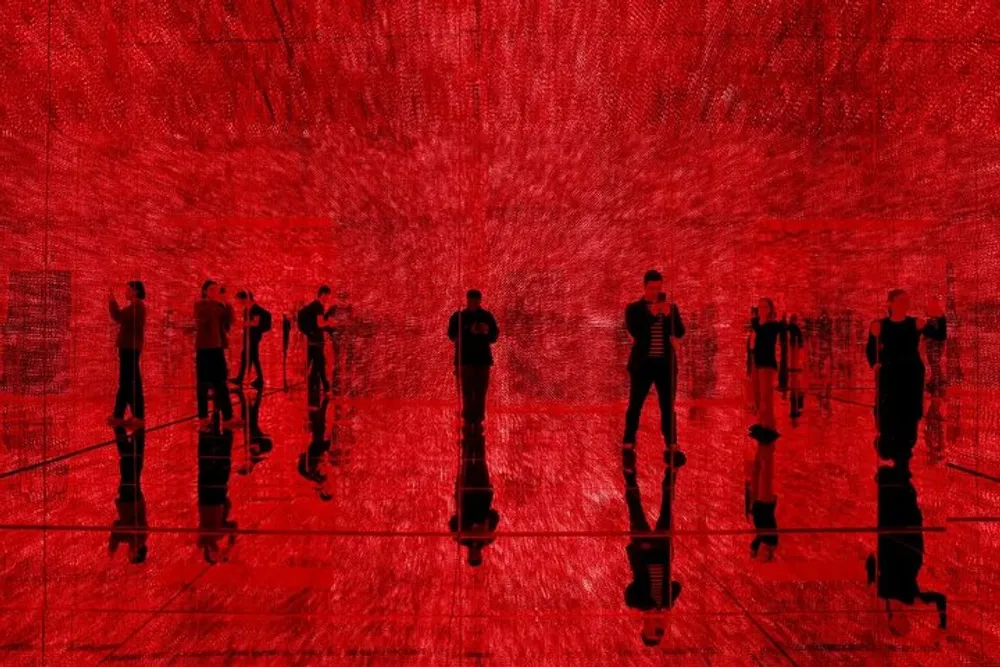 The image shows silhouetted figures standing in a reflective space bathed in a vivid red light creating an immersive monochromatic scene